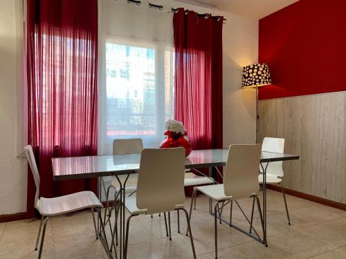バルセロナにあるLa Pedrera Residenceの赤いカーテン、テーブルと椅子付きのダイニングルーム
