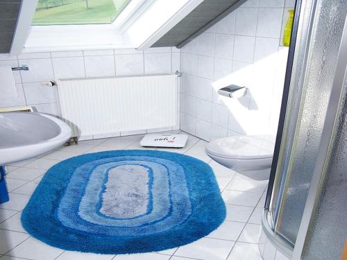 een badkamer met een blauw tapijt op de vloer bij Gästehaus Schoch in Bad Rippoldsau-Schapbach
