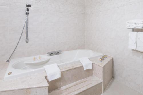 Baño blanco con bañera y lavamanos en Days Inn by Wyndham Hicksville Long Island en Hicksville