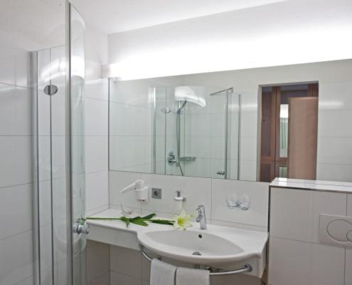 a white bathroom with a sink and a mirror at Hotel Sonnblick in Gaschurn