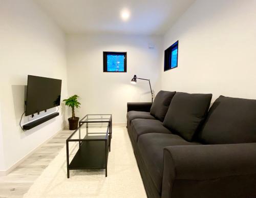 a living room with a couch and a tv at Chalet Villars in Hakuba