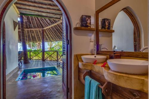 a bathroom with two sinks and a pool at SeVi Boutique Hotel in Matemwe