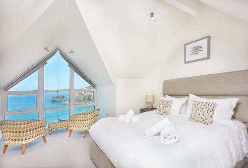 Dos camas en una habitación con una gran ventana. en Westaway, en Portreath