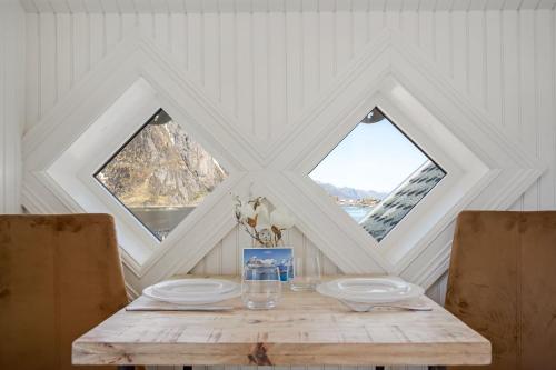 a wooden table with two plates and two windows at Sakrisøy Gjestegård - Manor House in Sakrisøy - Solbakken anno 1880 in Reine