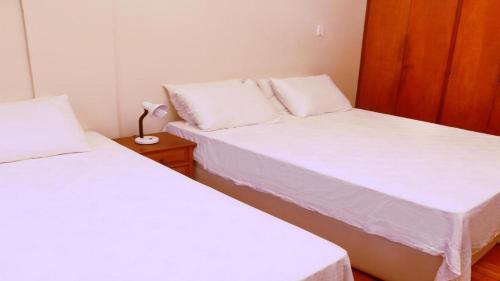 two beds in a small room with white sheets at Copacabana 4 pessoas Pertinho da Praia! in Rio de Janeiro