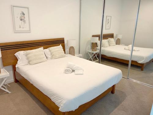 a bedroom with two beds with white sheets and mirrors at Perfect short term stay in Brissy Cozy & Relax in Brisbane