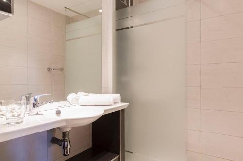 a white bathroom with a sink and a shower at The Originals Boutique, Hôtel Aquilon, Saint-Nazaire (Inter-Hotel) in Saint-Nazaire