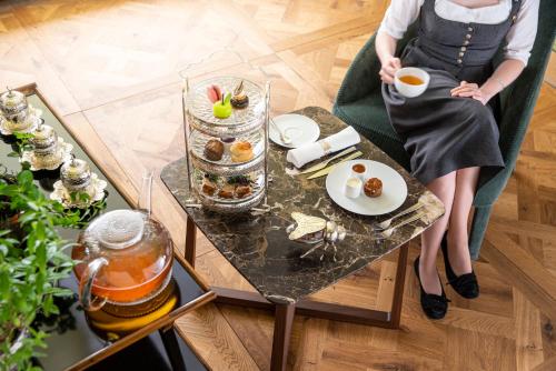 a woman sitting at a table with a plate of food at MalisGarten Green Spa Hotel - Adults Only in Zell am Ziller