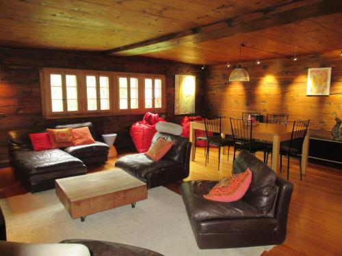a living room with leather chairs and a table and a dining room at Chalet historique de haut standing in La Tour