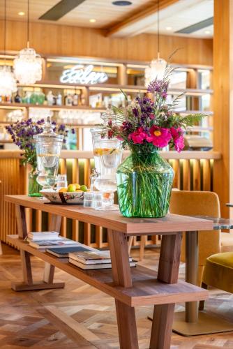 a wooden table with a vase of flowers on it at MalisGarten Green Spa Hotel - Adults Only in Zell am Ziller