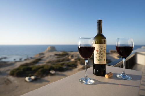 a bottle of wine and two glasses on a table at Sunset Seaview Apartments in Marsalforn