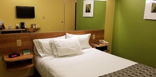 a bedroom with a white bed with a green wall at Microtel Inn & Suites by Wyndham Delphos in Delphos
