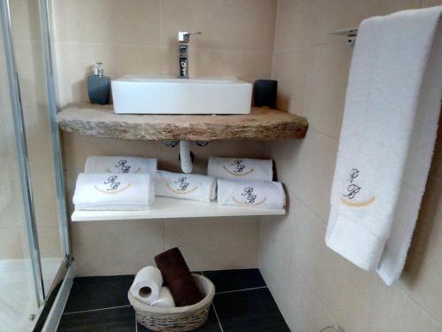 a bathroom with a sink and towels on a shelf at O Refúgio das Buracas in Condeixa a Nova