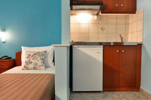 a small kitchen with a bed and a white refrigerator at Hotel Stefanos in Chrysi Ammoudia