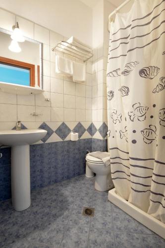 a bathroom with a sink and a toilet and a shower curtain at Hotel Stefanos in Chrysi Ammoudia