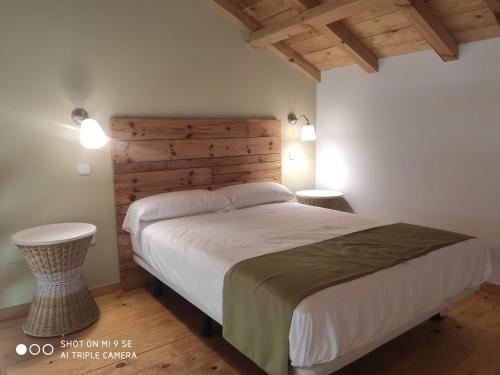 a bedroom with a large bed with a wooden headboard at Finca La Calancha in Cuerva