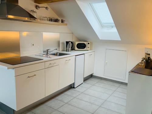 a white kitchen with a sink and a microwave at Ferienwohnung Munchen in Vaterstetten