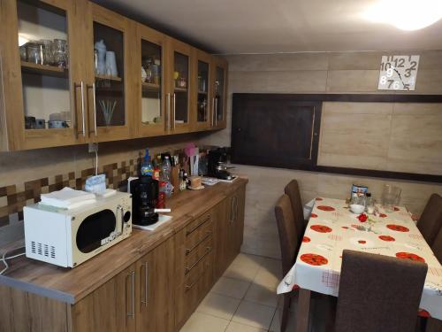 a kitchen with a table and a microwave in it at Szilvia Panzió Gyomaendrőd in Gyomaendrőd