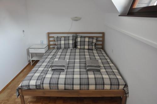 a bed with a plaid blanket and two pillows at Apartma Julija Hiška 59 in Čatež ob Savi