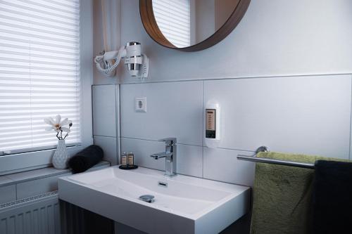 a bathroom with a white sink and a mirror at Pension Heimat in Ottenhöfen