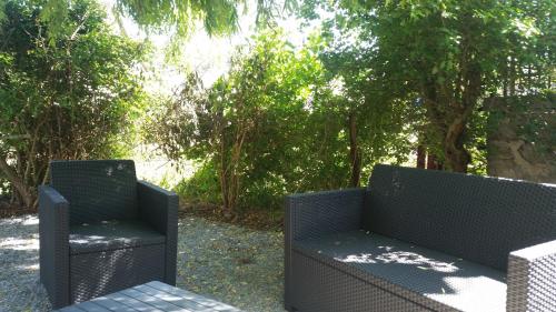 two black chairs sitting on a patio with trees at HOTEL L'AMERIVIERE*** in Aubrives