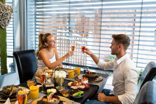 un hombre y una mujer sentados en una mesa bebiendo vino en Spa Villa Beauty & Wellness Resort en Wingerode
