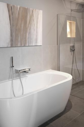 a white bath tub in a bathroom with a shower at SAXX Apartments "Goldberg Karree" in Hagen