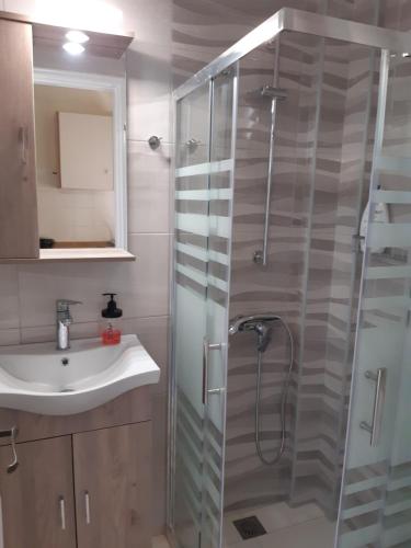 a bathroom with a glass shower and a sink at Georgia Apartments & Studios Corfu in Glyfada