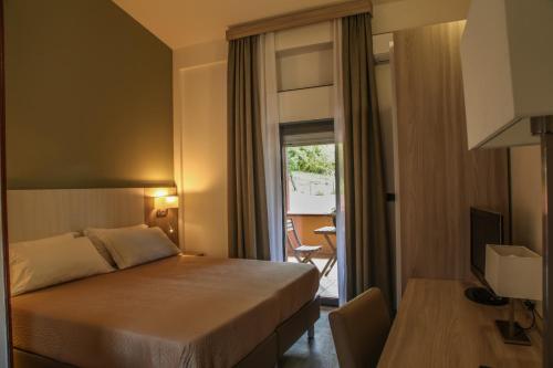 een hotelkamer met een bed en een balkon bij Pausania Inn in Tempio Pausania