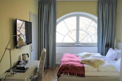a bedroom with a bed and a desk and a window at Rosersbergs Slottshotell in Rosersberg