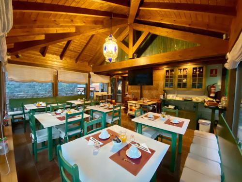 a restaurant with white tables and green chairs at Hotel La Cuna del Sella in Oseja de Sajambre