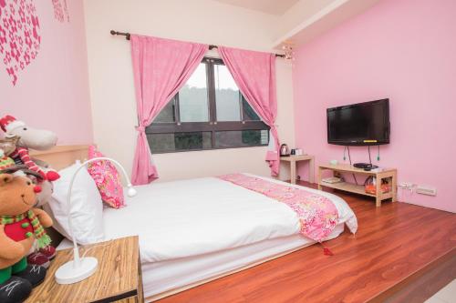 三義鄉的住宿－甘丹民宿-三義火車站前，粉红色的卧室配有床和电视