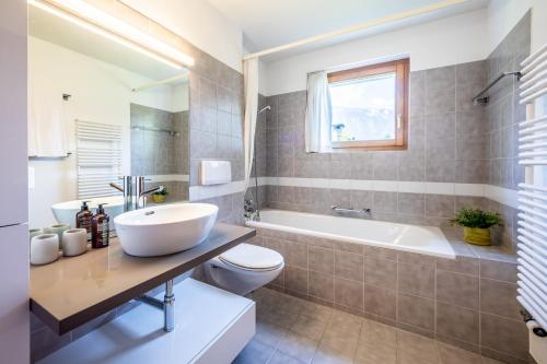 a bathroom with a sink and a tub and a toilet at Casa Alva - FLIMS in Flims