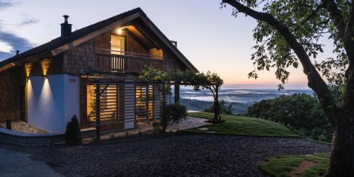 a house on a hill with the sunset in the background at steiRerBLiCke- Schilcherhaus in Greisdorf