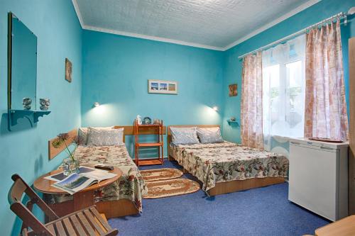 a room with two beds and a table and a window at Chernomor Guest House in Vityazevo