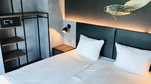 1 dormitorio con cama blanca y cabecero negro en SCOTTY & PAUL Hotel Deggendorf, en Deggendorf