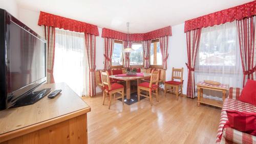 a living room with a table and chairs and a television at Residence Carin in Selva di Val Gardena