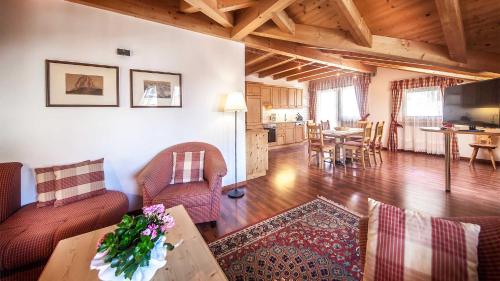 a living room with chairs and a table and a kitchen at Residence Carin in Selva di Val Gardena