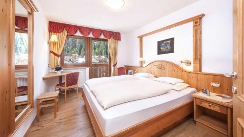 a bedroom with a bed and a desk and a window at Residence Carin in Selva di Val Gardena