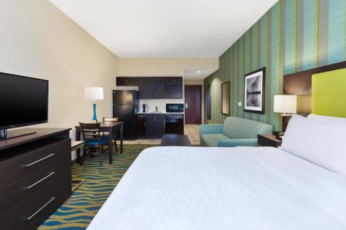 a hotel room with a large bed and a kitchen at Holiday Inn Express & Suites Southport - Oak Island Area by IHG in Oak Island