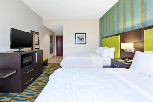 a hotel room with two beds and a flat screen tv at Holiday Inn Express & Suites Southport - Oak Island Area by IHG in Oak Island