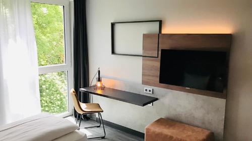 a bedroom with a bed and a desk with a tv at SCOTTY & PAUL Hotel Deggendorf in Deggendorf