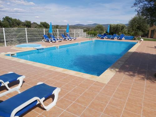 a swimming pool with blue lounge chairs next to it at Cidadelhe Rupestre Turismo Rural in Cidadelhe
