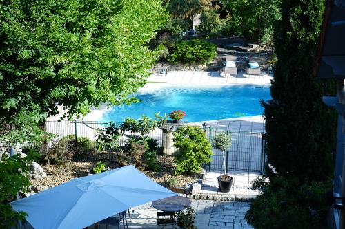 an overhead view of a pool with an umbrella at Logis Hotel Le Blason de Provence in Monteux