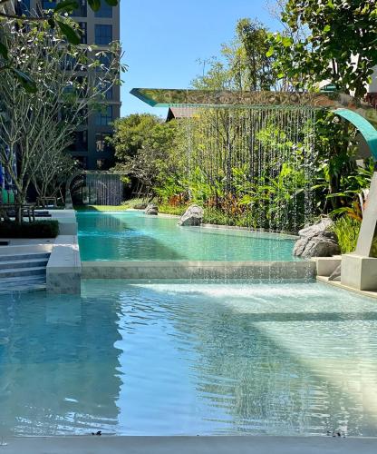 a swimming pool in a park with blue water at New Cosy Apartment at Marvest Huahin City Center in Hua Hin