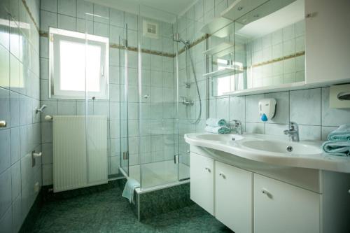 een witte badkamer met een wastafel en een douche bij Appartements Caroline in Ossiach
