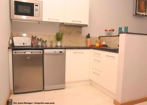 a kitchen with white cabinets and white appliances at Amber Apartments in Gdańsk