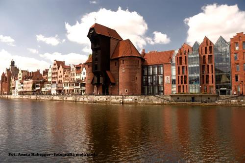 a building next to a body of water with buildings at Amber Apartments in Gdańsk