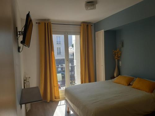 a bedroom with a bed and a large window at Hôtel Aunis-Saintonge in Royan