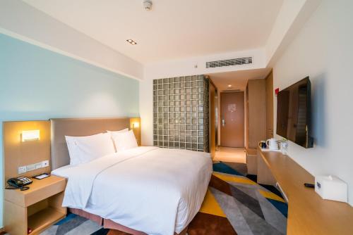 a hotel room with a large bed and a flat screen tv at Holiday Inn Express Chengdu Xindu by IHG in Chengdu